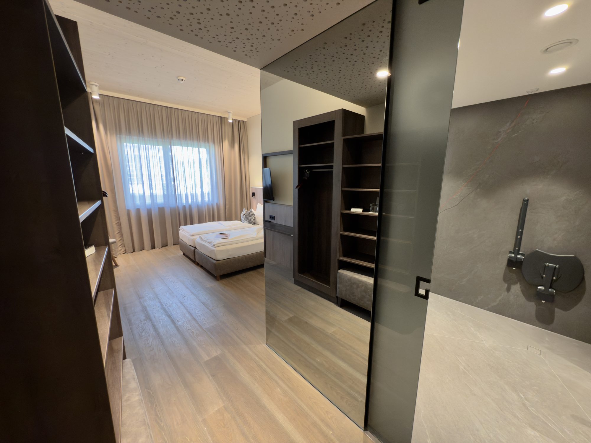 Barrierefreies Zimmer: die breite Schiebetür zwischen Bad und Zimmer steht offen, dahinter das Bett