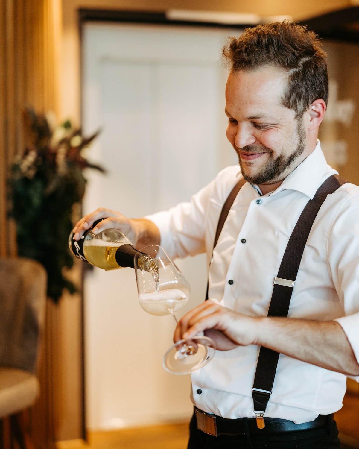 Philipp Weiglhofer-Russegger schenkt lächelnd ein Glas Wein ein