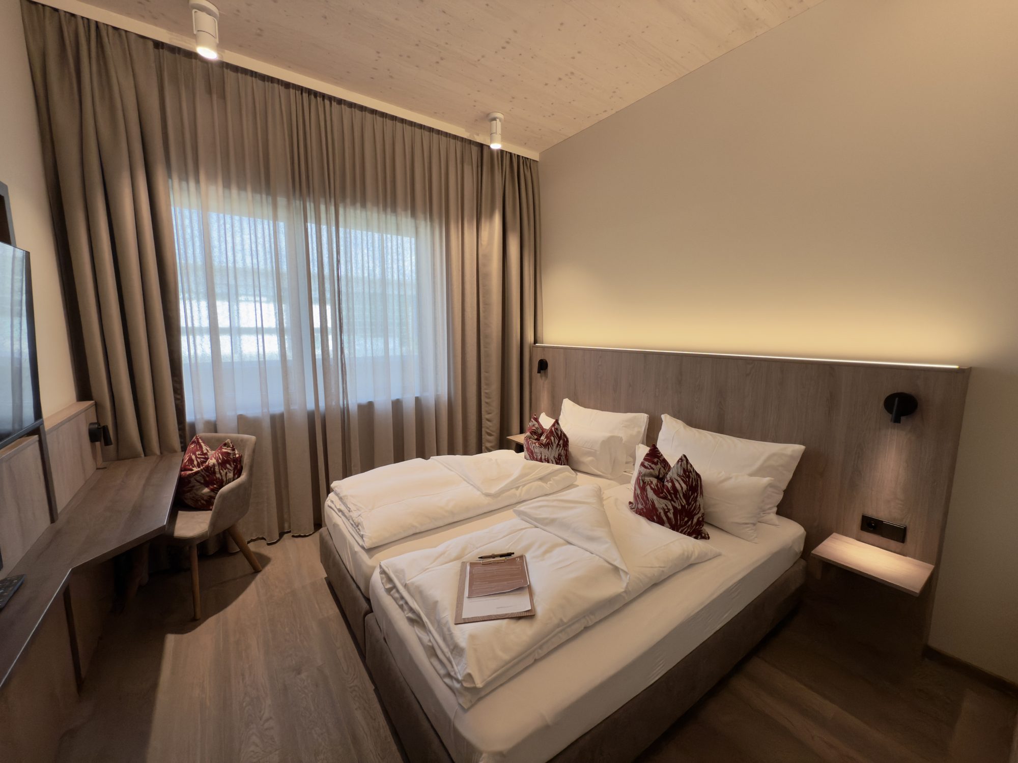 Standardzimmer mit 17 m²: Doppelbett, lange Ablage am Fenster und Fernseher