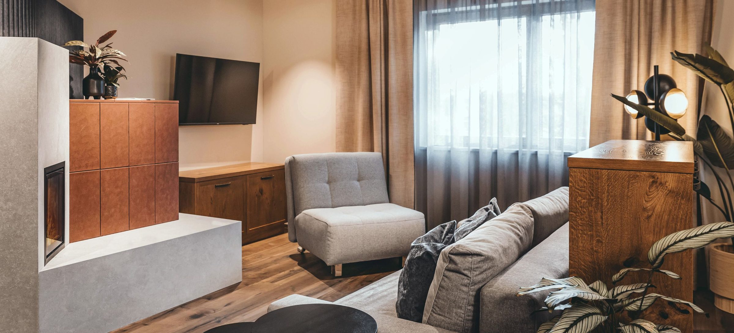Suite Infinita mit 60 m²: der frei im Raum stehende Kachelofen, davor Sofa und Sessel am Fenster