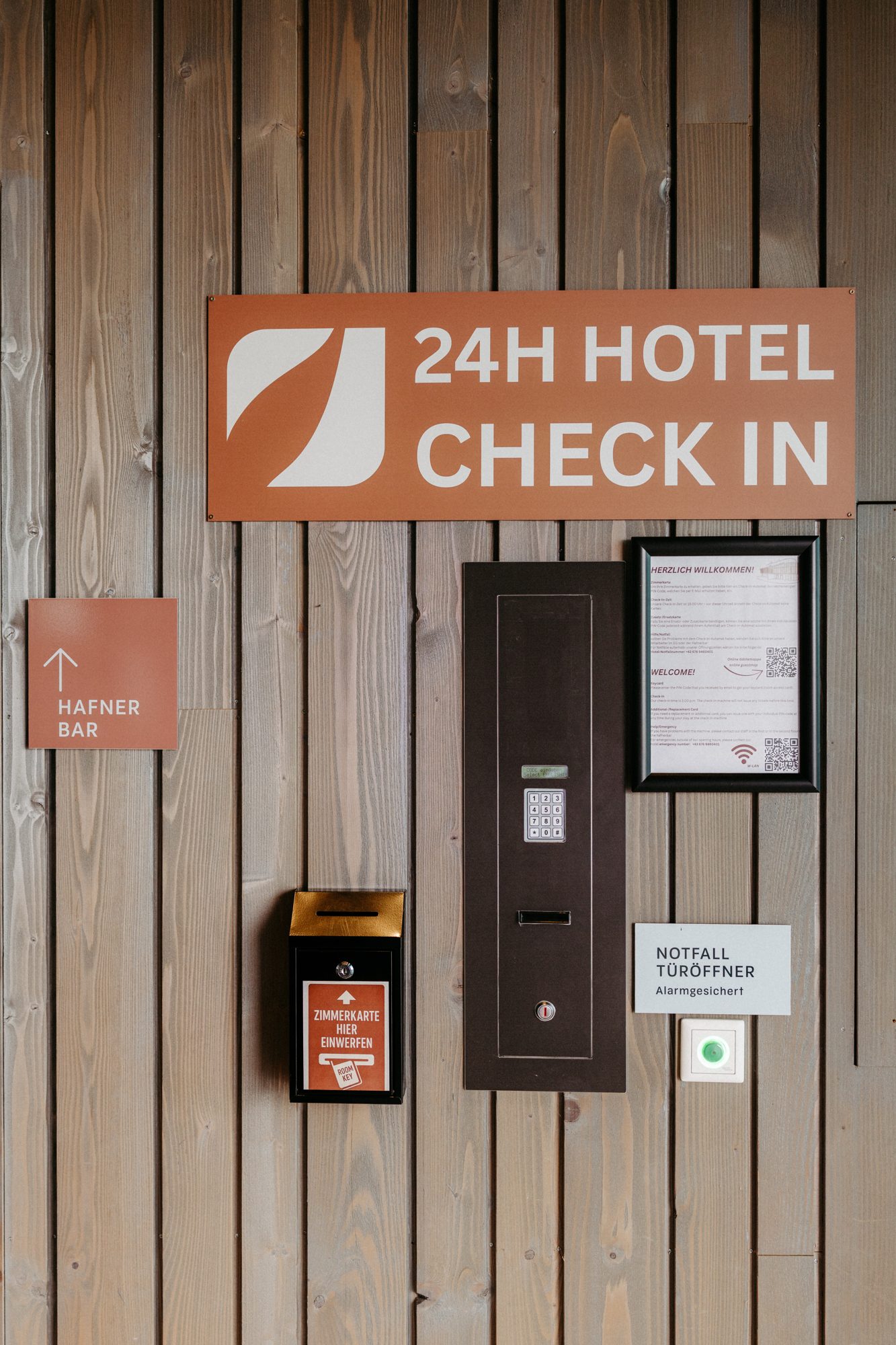 Schild 24h Hotel Check-in und Check-in-Automat an der Holzwand im Eingang